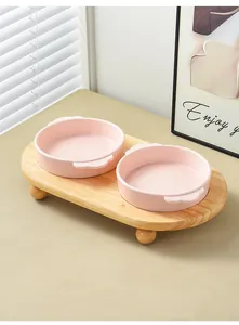 Detail showing two pink ceramic cat bowls on an elevated natural wooden stand base