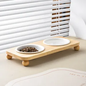 Minimalist white ceramic double pet bowl with wooden stand and spherical feet for cats