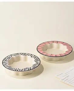 Detail van keramische voerbakken met gegolfde rand, zebra- en roze streeppatroon