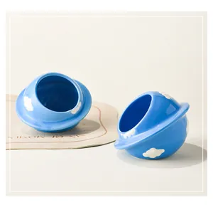 Macro detail of sky blue ceramic hamster hideout with white cloud patterns and tilted design