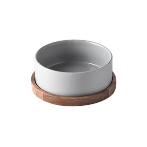 Minimalist grey ceramic pet bowl with natural acacia wood base on white background