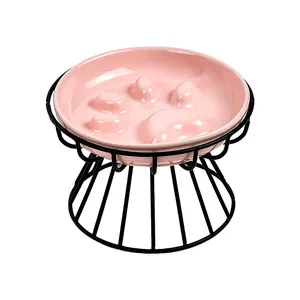 Pink ceramic slow feeder cat bowl with paw pattern on a raised black metal stand