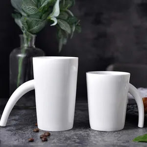 Detailed view of two white ceramic mugs with unique long curved handles on stone background