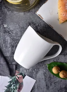 Minimalist white ceramic coffee mug with rounded handle on marble surface lifestyle view