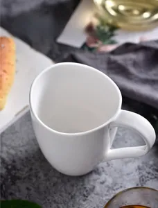 Detail view of smooth white ceramic coffee mug handle on textured marble tabletop
