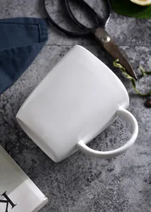 Nahaufnahme der weißen Keramiktasse mit dickem Rand und ergonomischem Griff auf Stein