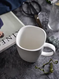 Draufsicht einer weißen minimalistischen Keramiktasse auf dunkler Steinoberfläche