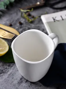 Makroaufnahme einer weißen Keramiktasse mit transparenter Glasur auf Marmoroberfläche