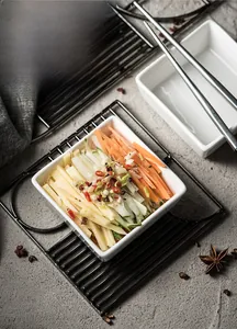 Square white ceramic bowl containing fresh vegetables on a modern stone table