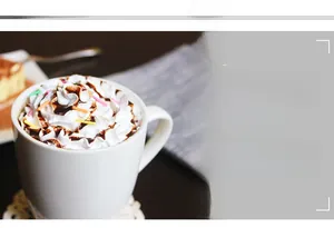 Close-up of a white ceramic coffee mug with whipped cream topping on a lace coaster