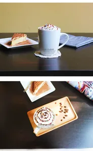 White ceramic coffee mug on a dark wood tray with latte art and dessert setting