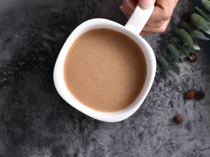 Detail einer weißen Keramik-Tasse mit Kaffee auf grauem Stein-Hintergrund-Textur