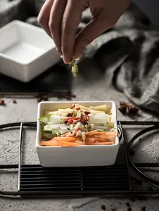 Macro detail of square white ceramic sauce bowls with shredded fresh vegetables