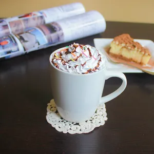 Minimalist white ceramic coffee mug with lace coaster on dark wood table setting