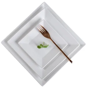 Three-piece set of minimalist white ceramic square plates in various sizes with rose gold fork