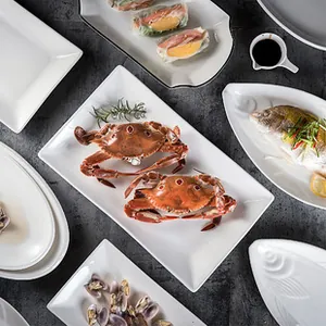 Flat lay of white ceramic serving plates with seafood and marble background texture