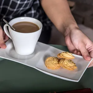 Dettaglio del set tazza da caffè in ceramica bianca con vassoio e cucchiaio in metallo