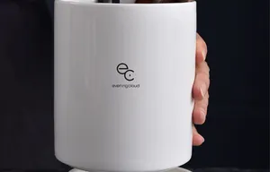 Κοντινό πλάνο λευκής κεραμικής θήκης εργαλείων κουζίνας με λογότυπο και λιτό σχέδιο