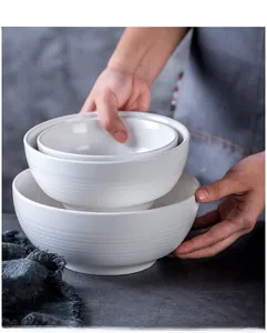 Detail of white ceramic bowls with tiered texture held by hands in a modern setting
