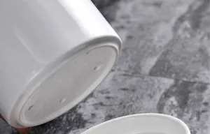 Detail of white ceramic holder with drainage holes showing heat resistance up to 180 degrees