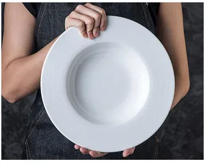 Close-up of minimalist white ceramic pasta plate with a wide ribbed edge held by hands