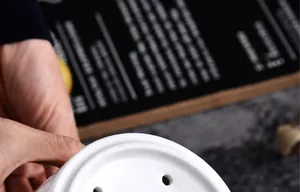 Close-up of a white ceramic holder with drainage holes for kitchen utensil storage
