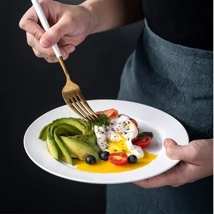 Set di piatti in ceramica bianca con forchetta dorata e toast all'avocado e salmone