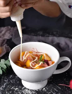 Close-up of white ceramic pedestal bowl with sauce pouring into healthy cereal dessert