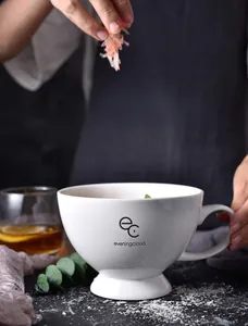 Detail of white ceramic mug with high base design and custom eveningcloud logo print