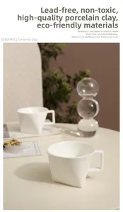 Close-up of a white ceramic coffee mug featuring a geometric base and square handle