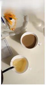 Close-up of white ceramic coffee mugs showing smooth glazed texture and tea pouring