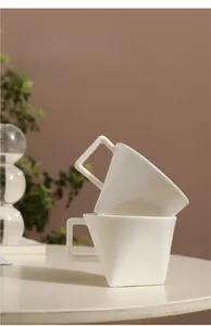 Detail of white ceramic coffee mug with unique geometric handle and smooth matte finish