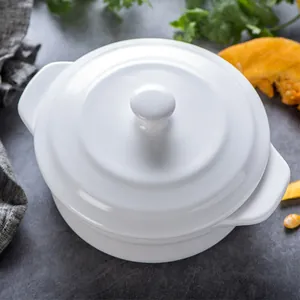 White ceramic stew pot with lid and double handles on a rustic kitchen countertop