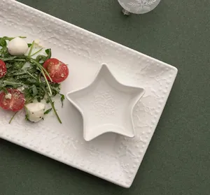 White ceramic tray and star bowl with winter elk snowflake relief on green background