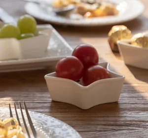 Star shaped white ceramic dipping bowl with fresh red cherry tomatoes on wooden table