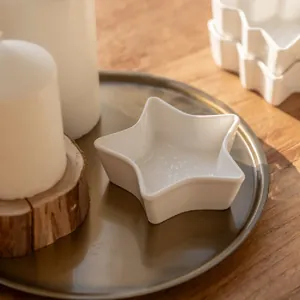 Star-shaped white ceramic snack bowl with relief pattern on elegant brass tray