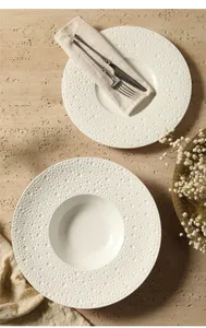 Detail van een crèmewitte keramische pastaschotel met reliëf van stippen op de rand