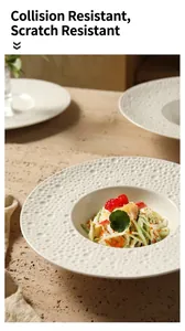 Detail van een crèmekleurig diep keramisch bord met bellenstructuur rand en salade