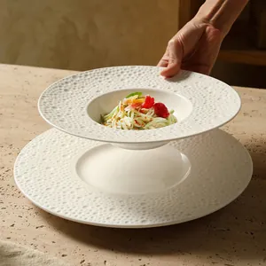 Minimalistisch wit keramisch pastabord met hamerslagpatroon en verse groene salade