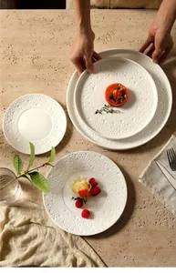 Detail of white ceramic dinner plate with embossed dotted texture on a stone surface