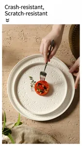 Detail of cream ceramic dinner plates featuring elegant pearl embossed texture and stackable design