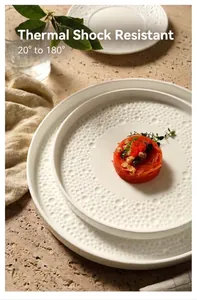 Detail of white ceramic dinner plates showing textured bubble relief and heat resistance