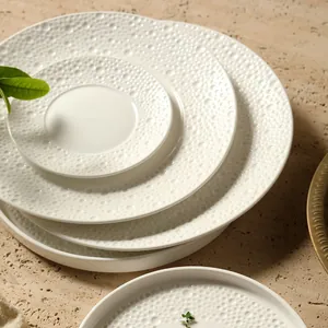 Modern white ceramic round plates set with minimalist embossed bubble pattern texture