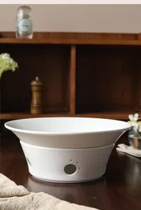 Close-up of white ceramic warming base featuring a decorative cat paw shaped air vent hole