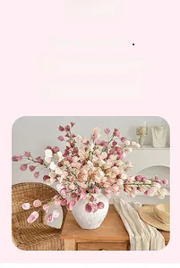Detail of pink and white faux Physalis branches in a white textured ceramic vase