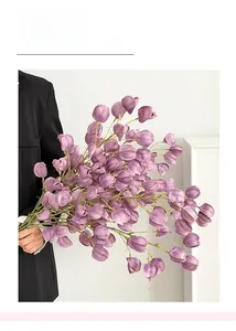 Detailed close-up of realistic purple faux lantern fruit branch held by a person