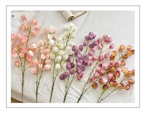 Macro shot of realistic artificial physalis branches in assorted colors on soft fabric