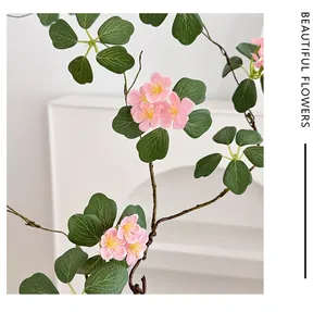 Primer plano de flores artificiales rosas con estambres amarillos y hojas verdes de casa