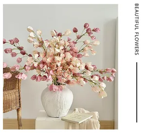 Detail of pink and cream faux lantern fruit flowers in a textured white ceramic vase