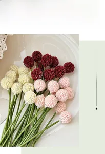 Detail of cream, burgundy, and pink pom-pom flowers in a white tray for home decor